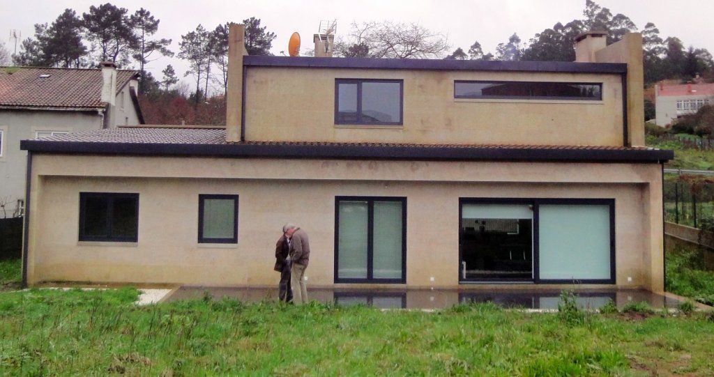 Una pareja parada frente a una casa grande