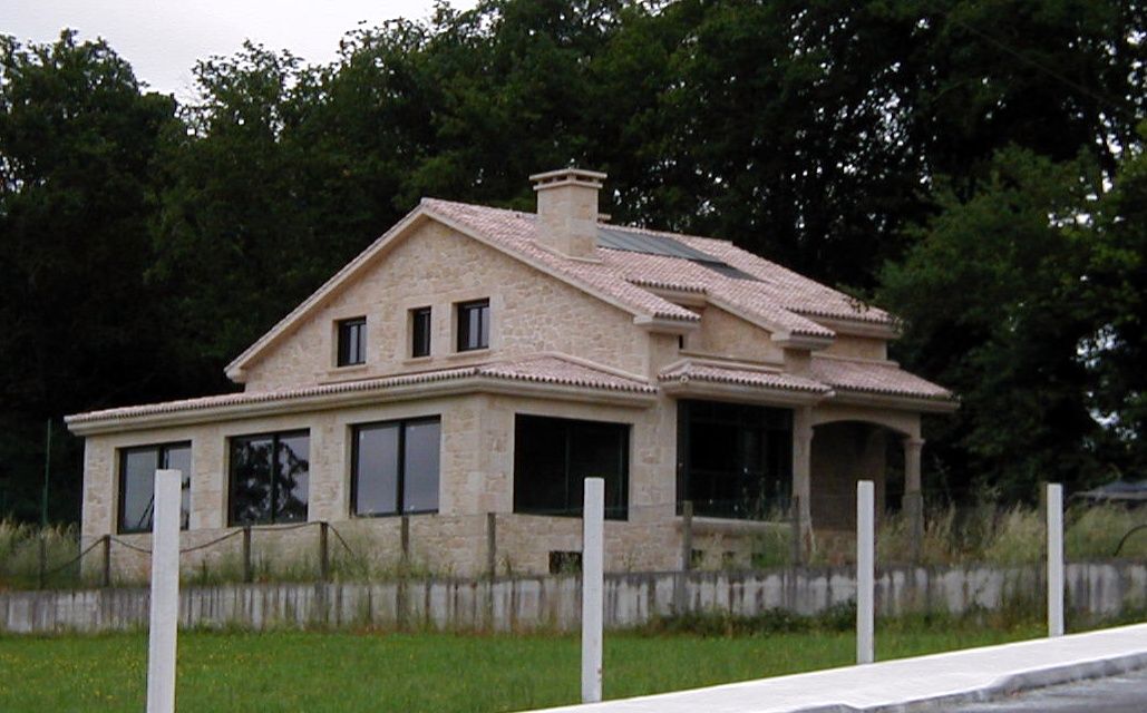 Una casa con techo rosa está rodeada de árboles.