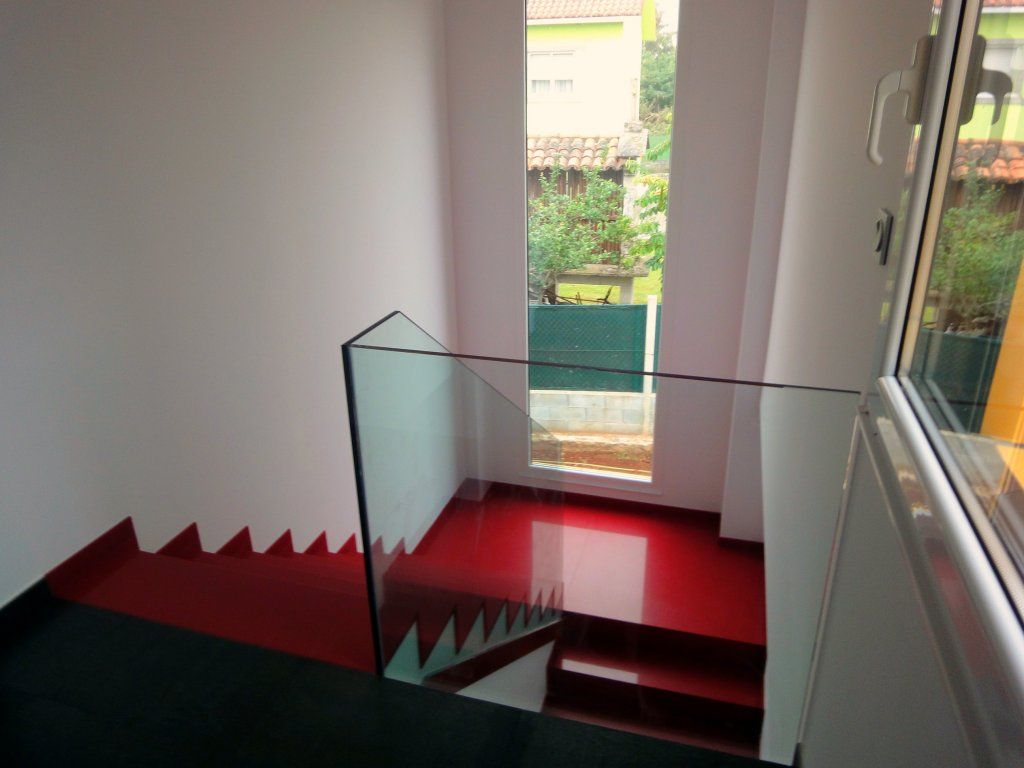 Una escalera con escalones rojos y barandilla de cristal.