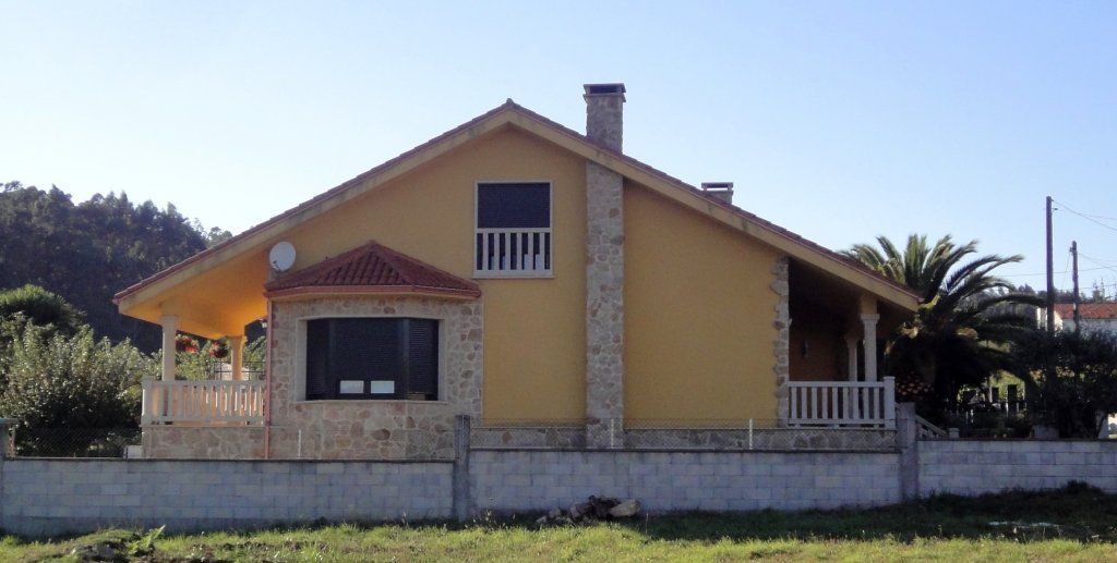 Una casa amarilla con una valla de ladrillos alrededor