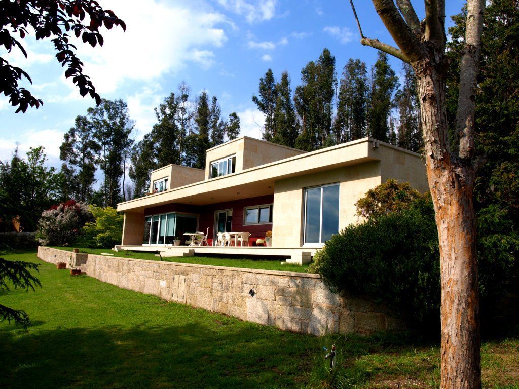Una casa grande con muchas ventanas está rodeada de árboles.