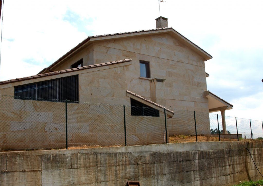 Una gran casa de piedra con una valla alrededor.