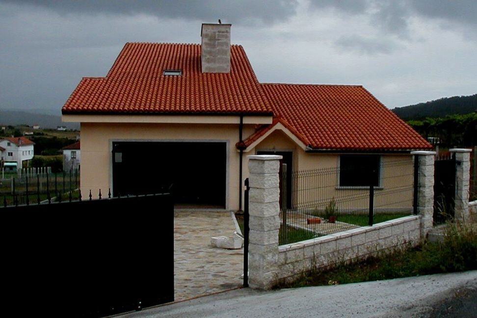 Una casa con techo de tejas rojas y garaje