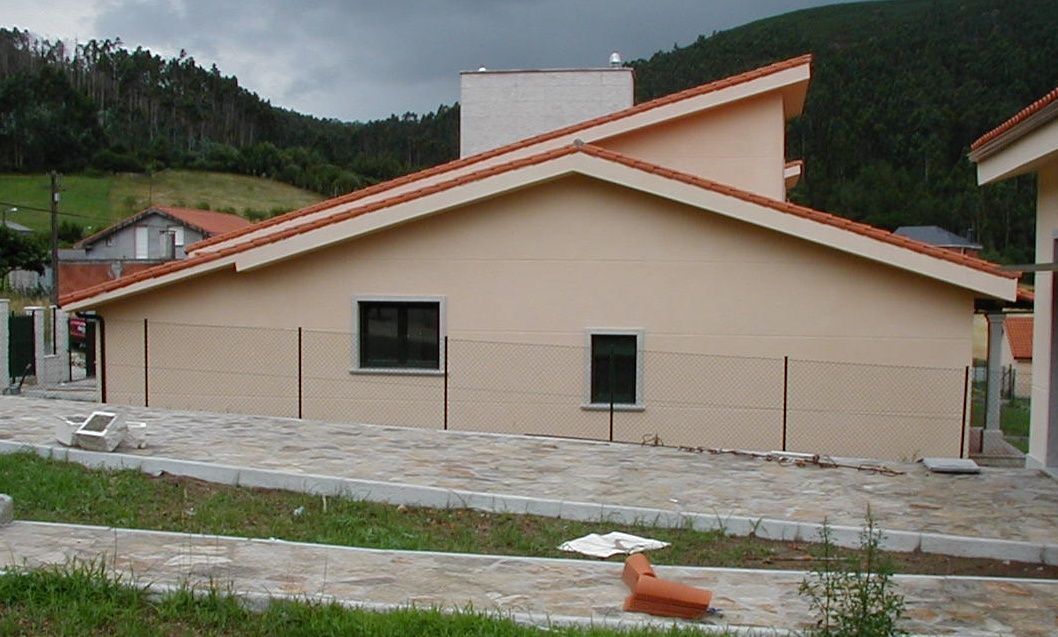 Una casa con techo de tejas rojas y una valla delante