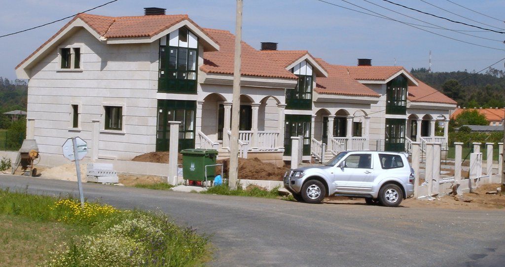 Una camioneta blanca está estacionada frente a un edificio en construcción.