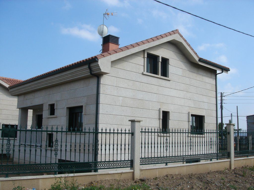 Una casa con una valla alrededor y una antena parabólica en el tejado