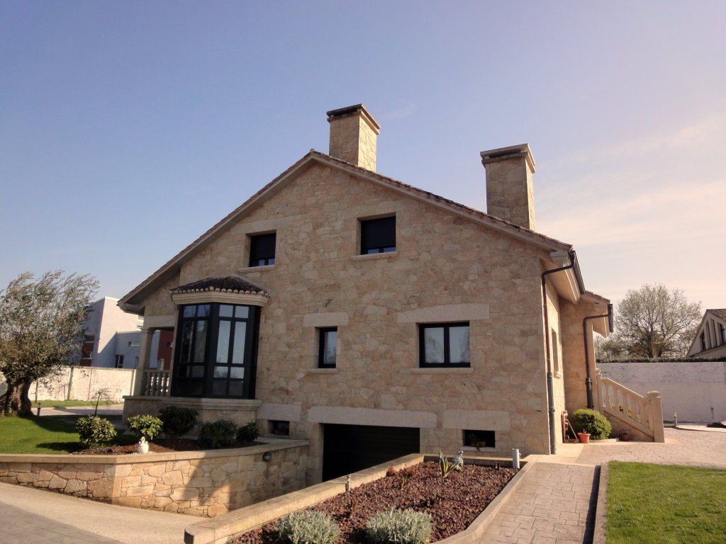 Una gran casa de piedra con un garaje debajo.