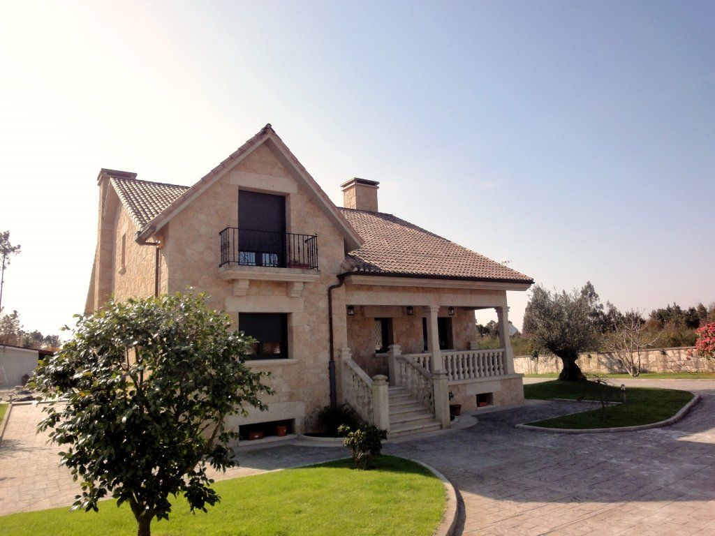 Una casa grande con un balcón y un árbol delante.
