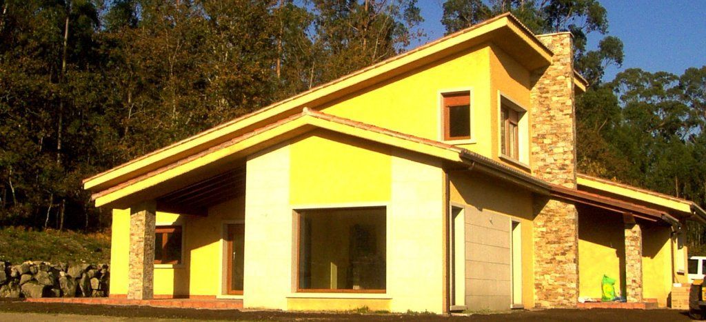 Una casa amarilla con techo de tejas está rodeada de árboles.