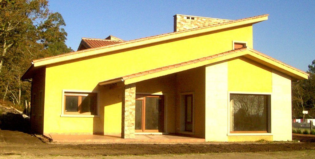 Una casa amarilla con techo de tejas y muchas ventanas