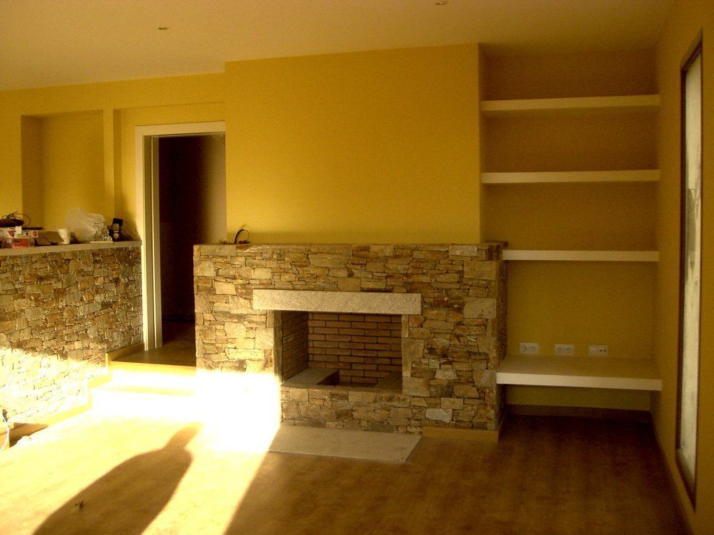 Una sala de estar con paredes amarillas y una chimenea de piedra.