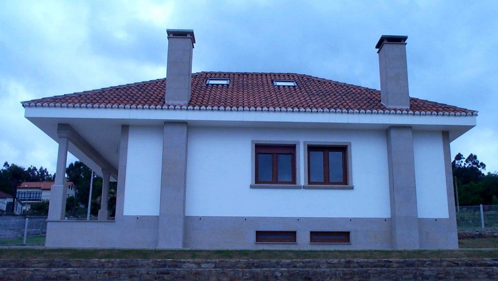 Una casa blanca con techo de tejas rojas y chimeneas
