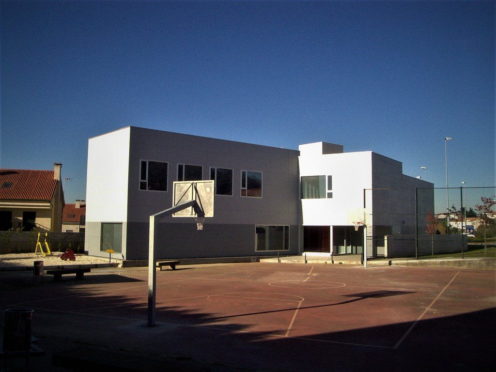 Un edificio blanco con un aro de baloncesto delante.