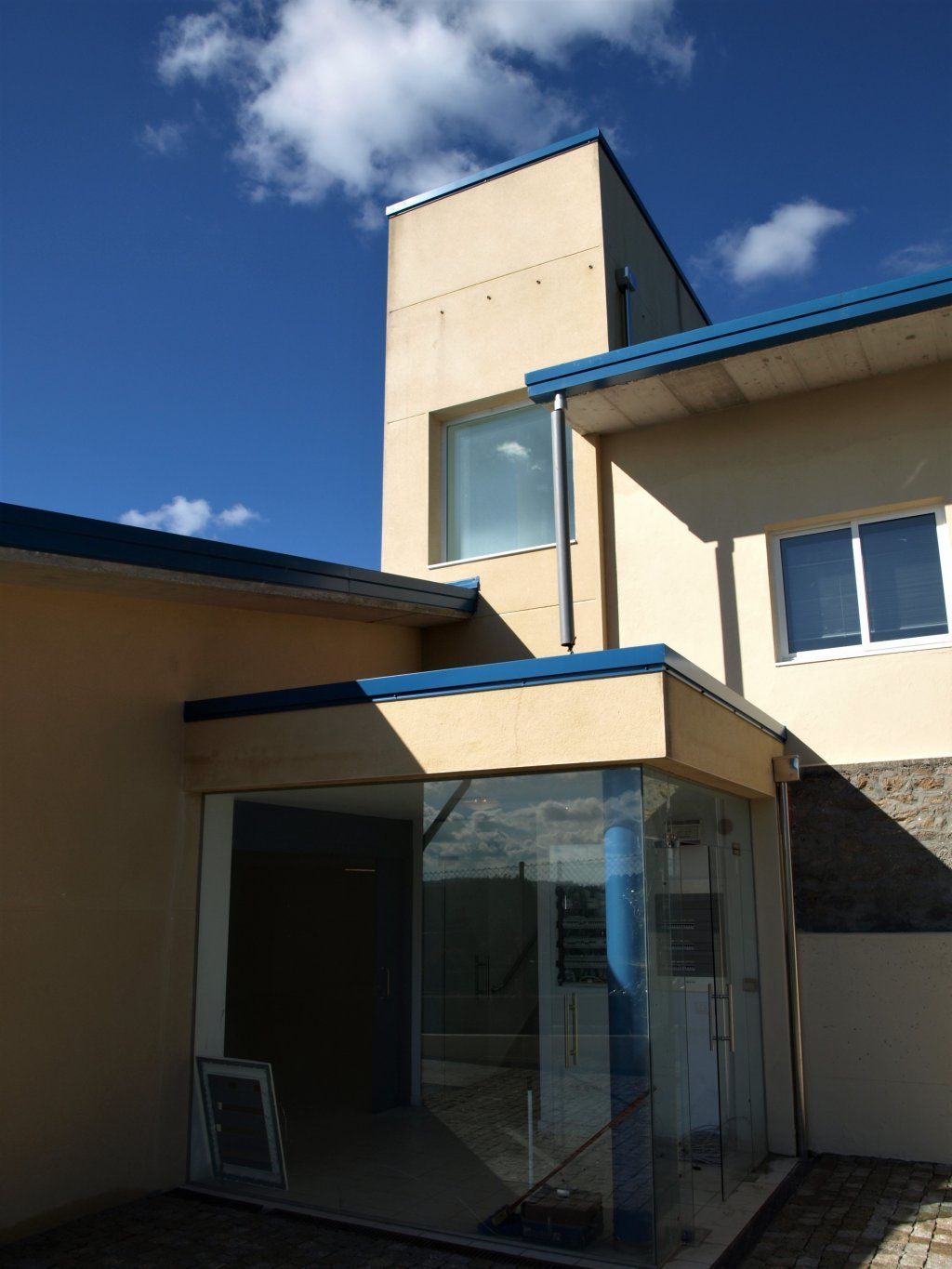Un edificio con techo azul y entrada de cristal.