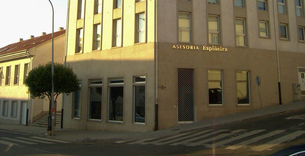 Un gran edificio con muchas ventanas está en la esquina de una calle.