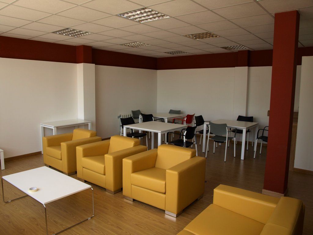 Una sala de estar con sillas y mesas amarillas.