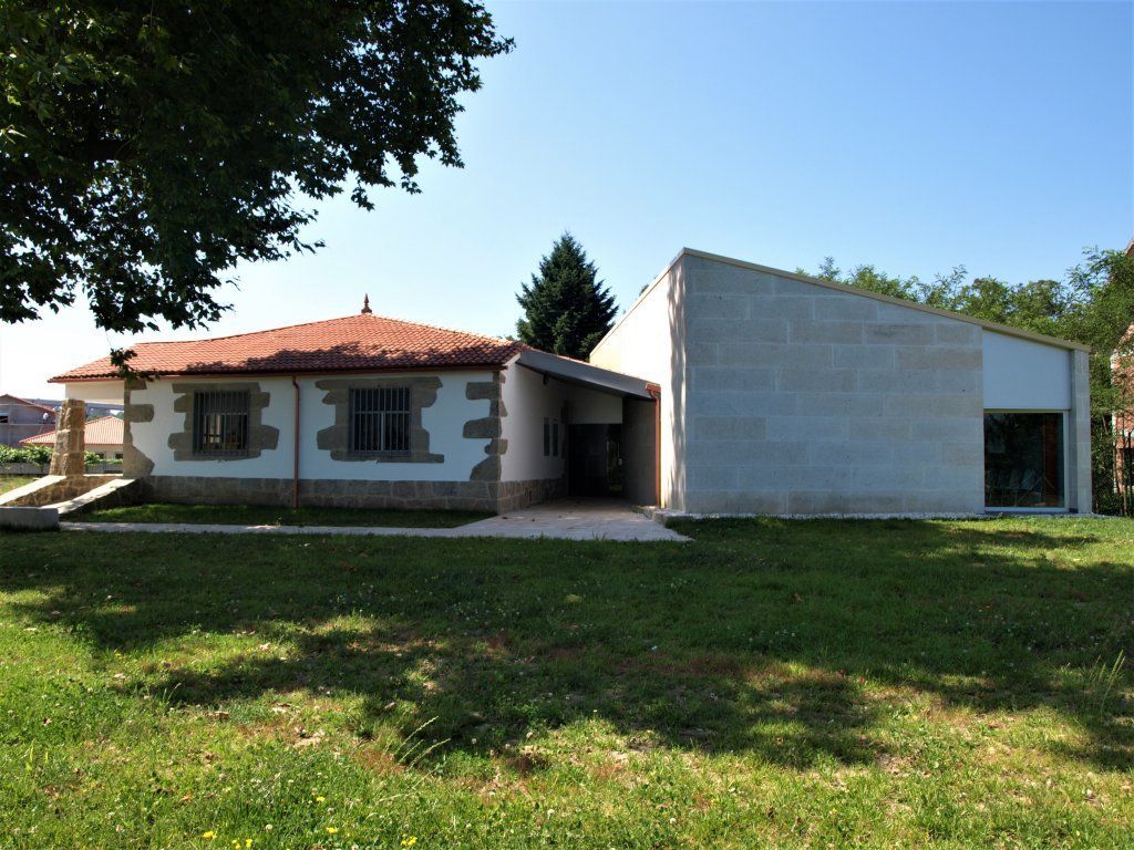 Una casa blanca con techo rojo se encuentra en medio de un exuberante campo verde.