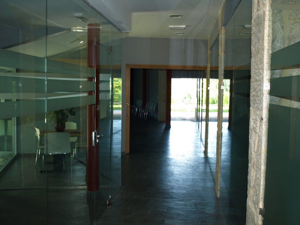 Un pasillo en un edificio con paredes y puertas de vidrio.