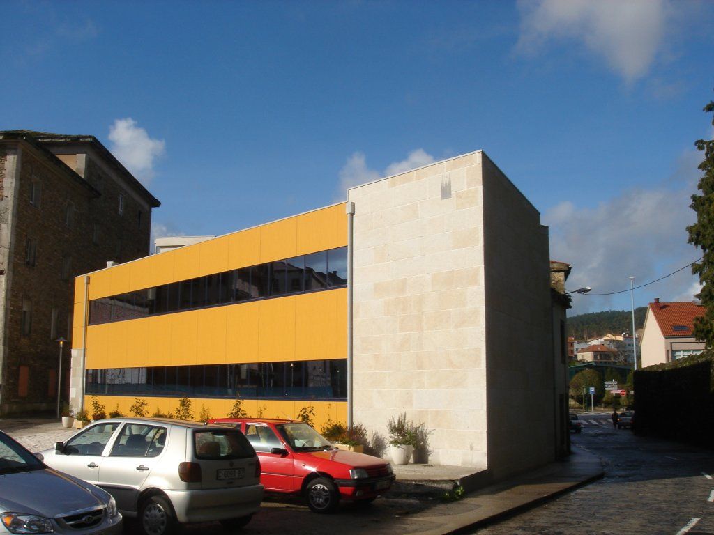 Un edificio amarillo con coches aparcados delante.