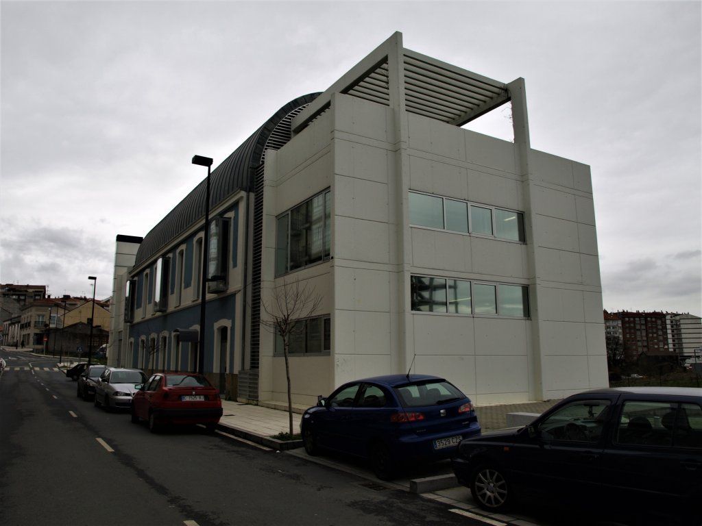 Un coche azul está aparcado delante de un gran edificio blanco.