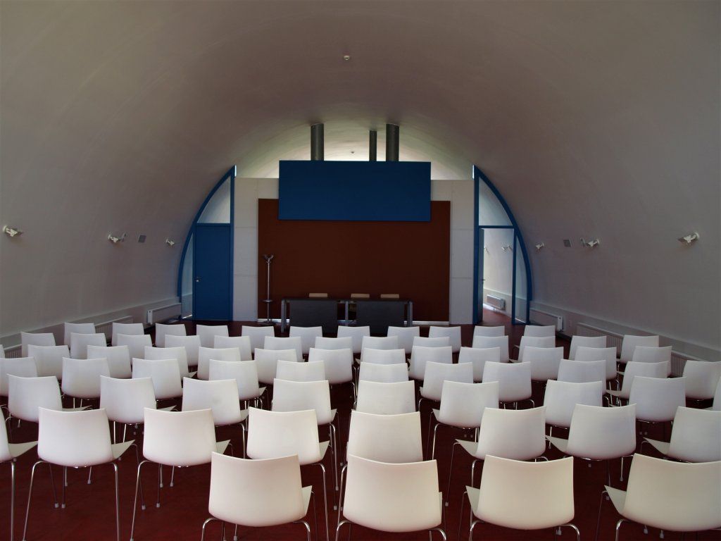 Filas de sillas blancas en una habitación con una pared azul