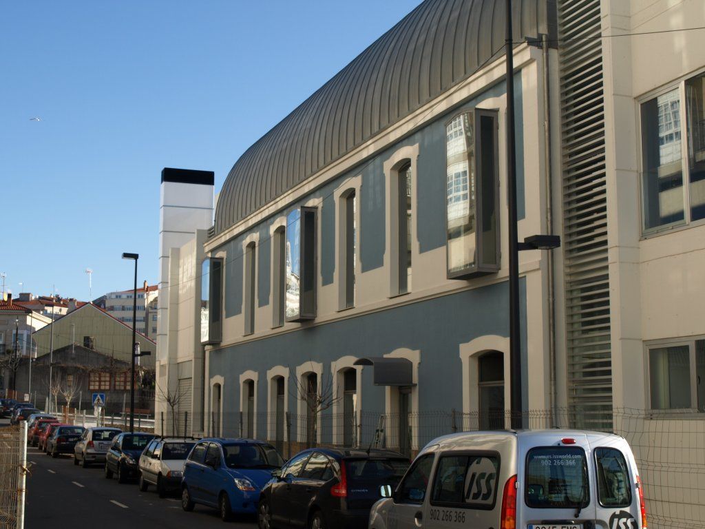 Una fila de coches están aparcados delante de un gran edificio.