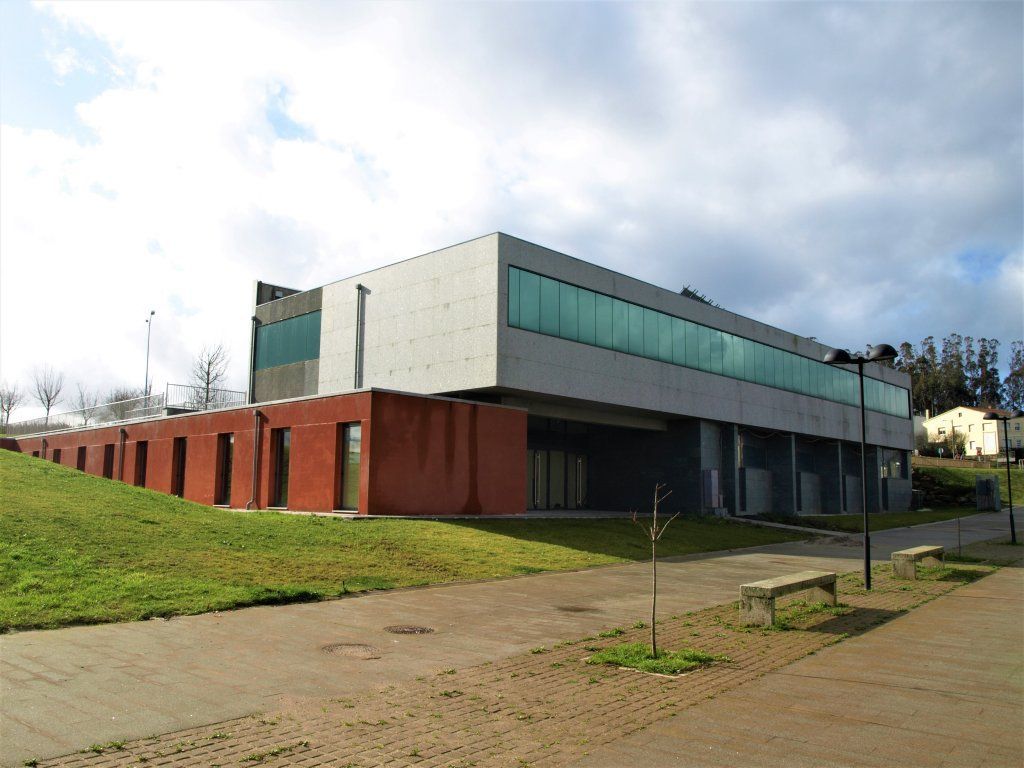 Un gran edificio con muchas ventanas se encuentra en la cima de una colina cubierta de hierba.