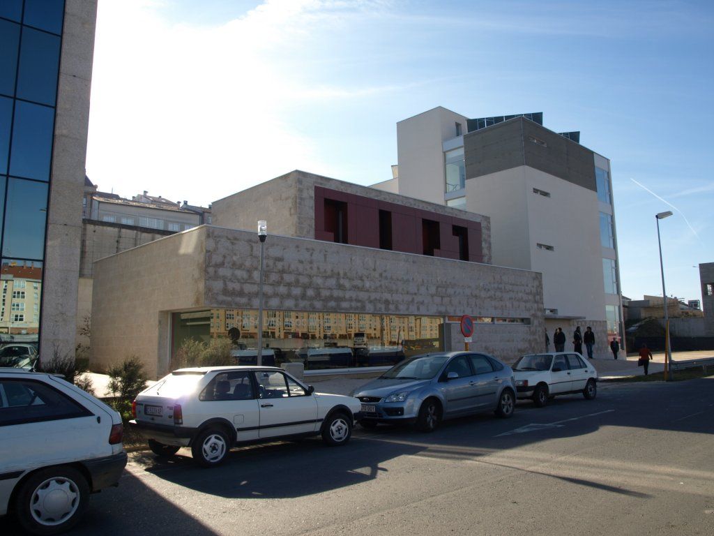 Una fila de coches están aparcados delante de un edificio.