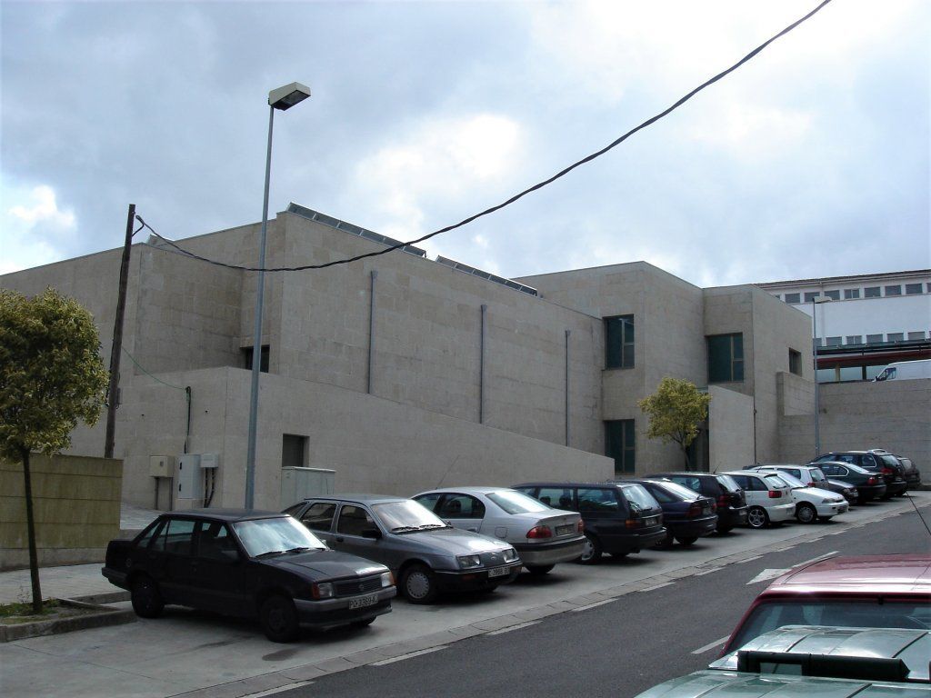 Una fila de coches están aparcados delante de un edificio.