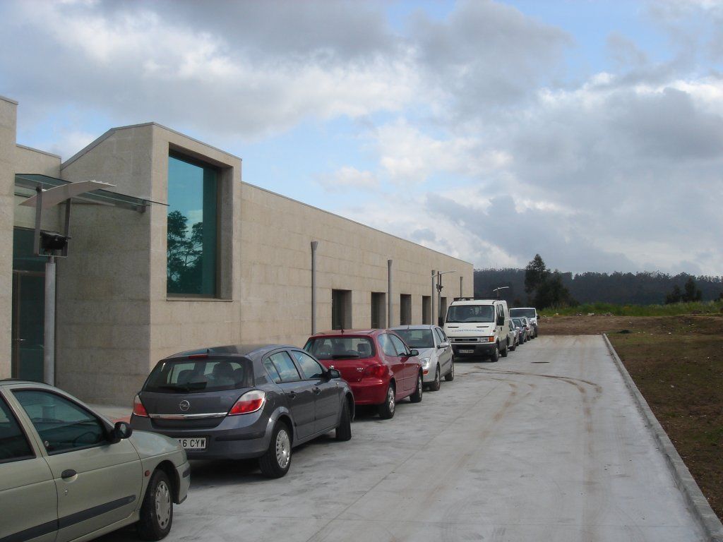 Una fila de coches están aparcados delante de un edificio.