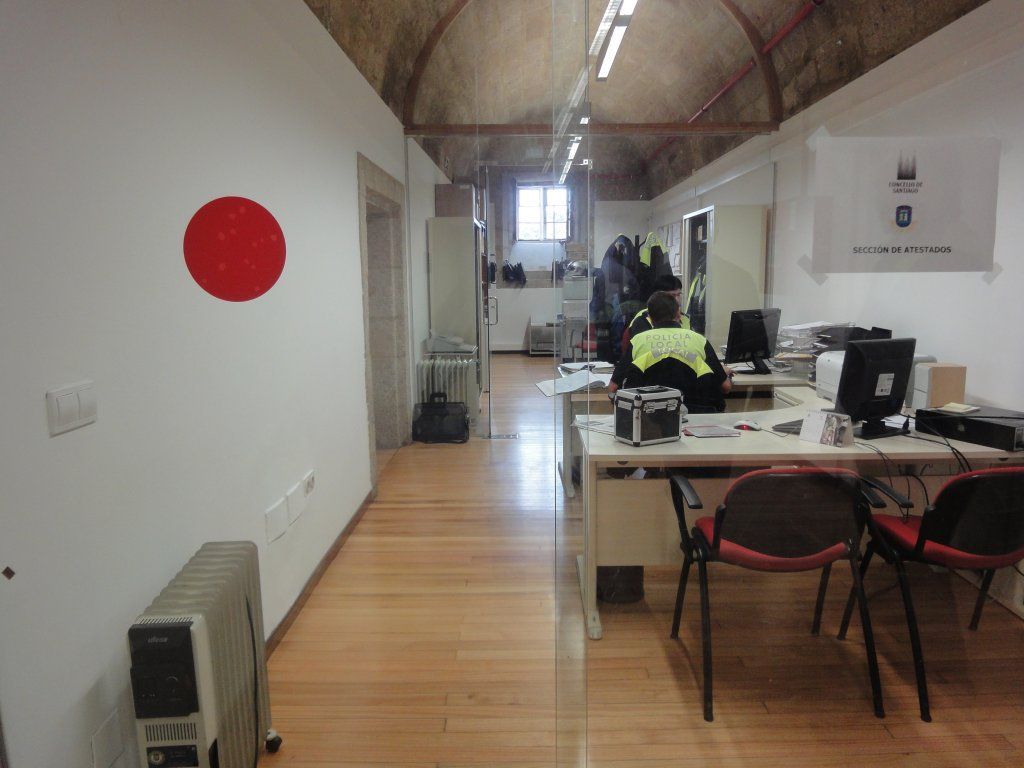 Un hombre está sentado en un escritorio en una oficina con un círculo rojo en la pared.