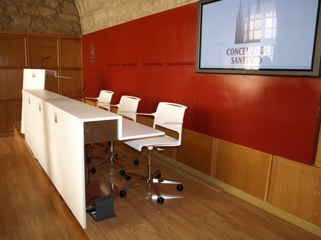 Un podio y sillas delante de una pared que dice Consell de Sant Jordi