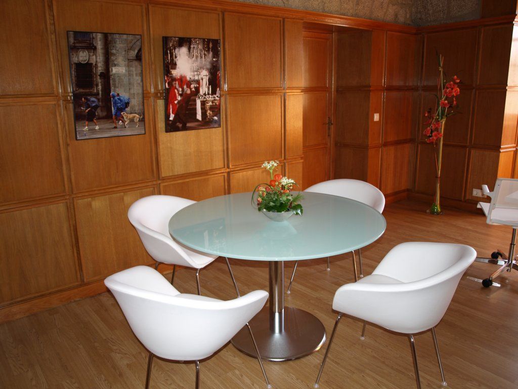 Una habitación con una mesa redonda y sillas blancas.