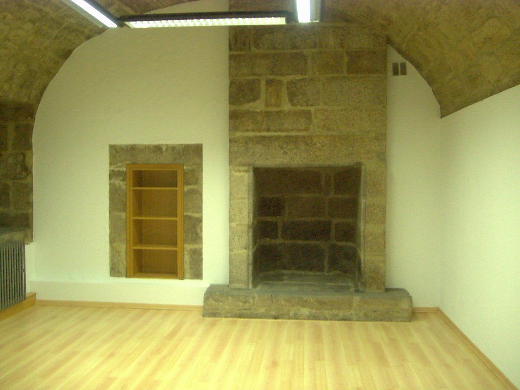 Una habitación vacía con una chimenea de piedra y estantes.