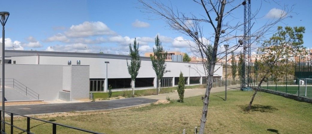 Un área cercada con árboles y un edificio al fondo.