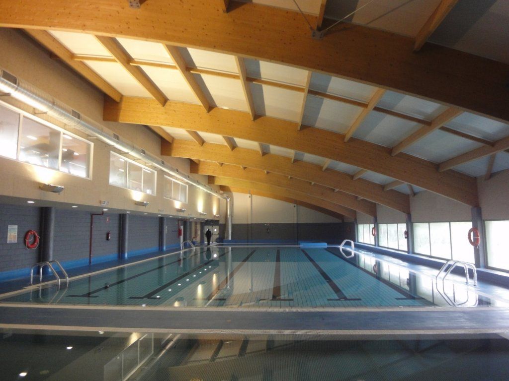 Una gran piscina cubierta con techo de madera.
