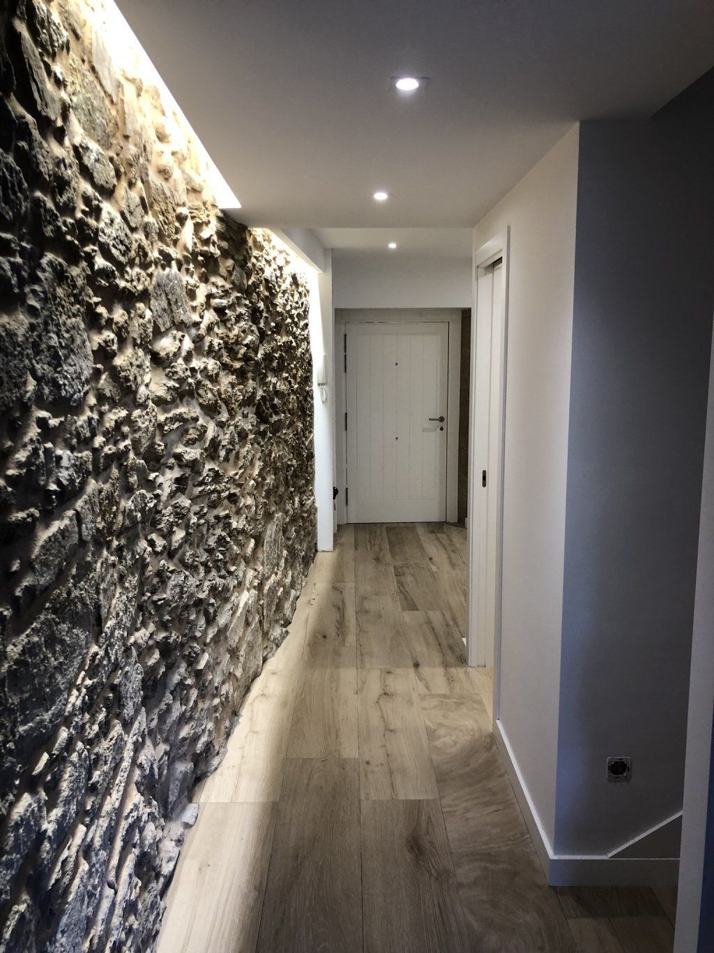 Un pasillo con una pared de piedra y un suelo de madera.