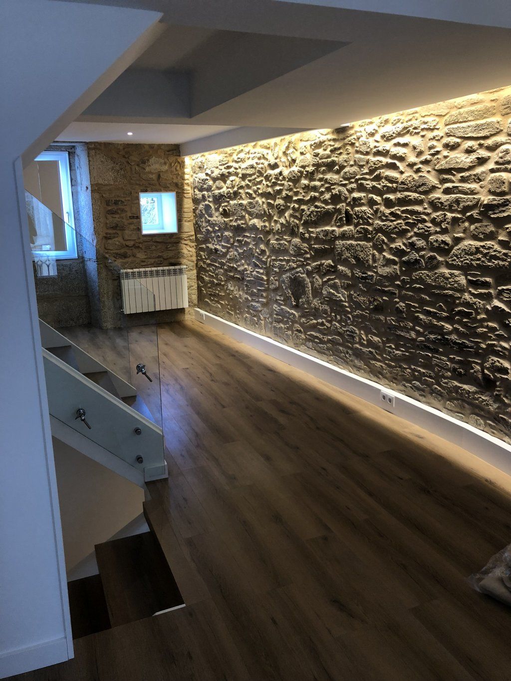 Una habitación con una pared de piedra y un suelo de madera.