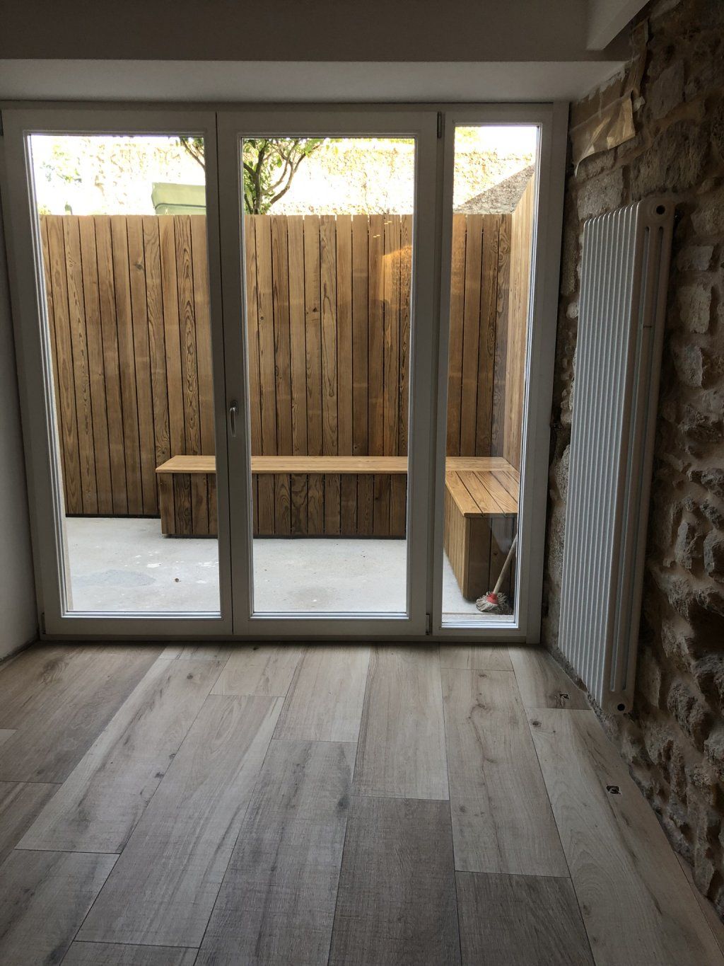 Una habitación vacía con un banco de madera y puertas corredizas de vidrio.