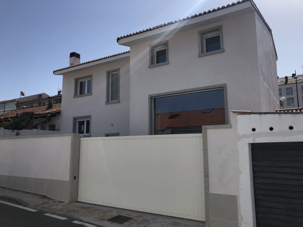 Una casa blanca con una valla blanca y un garaje delante de ella.