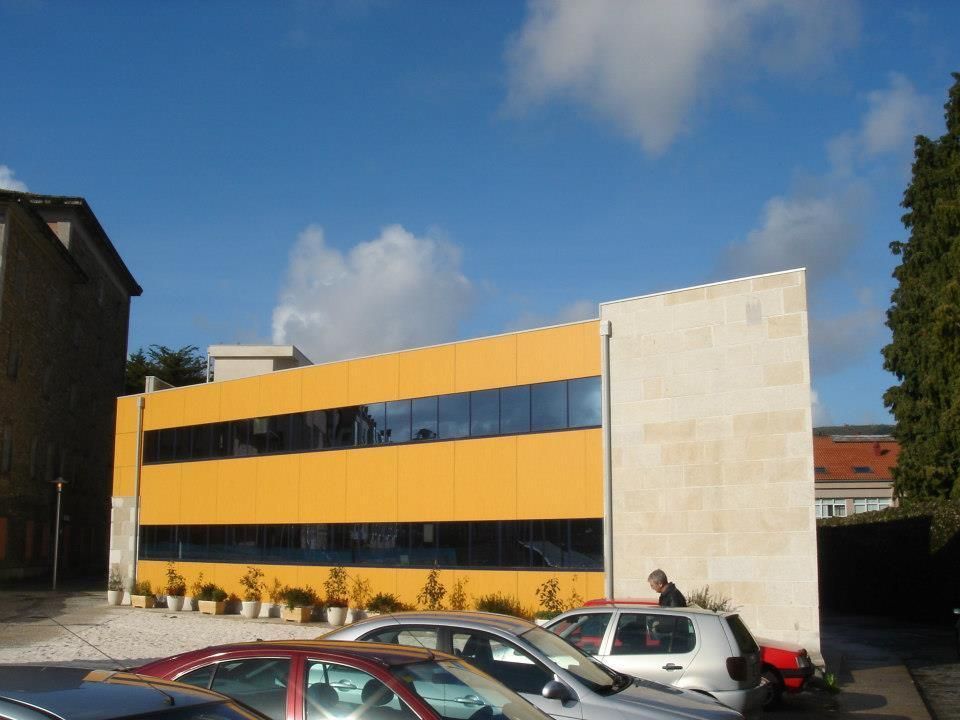 Un edificio amarillo con coches aparcados delante.