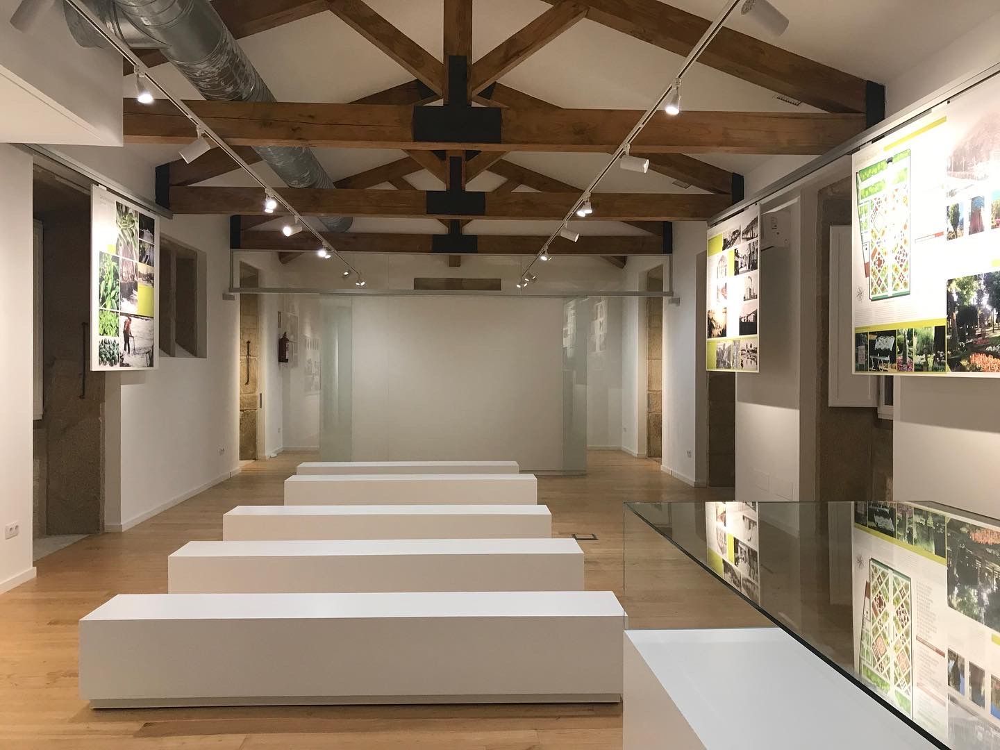 Una gran habitación vacía con vigas de madera y bancos blancos.