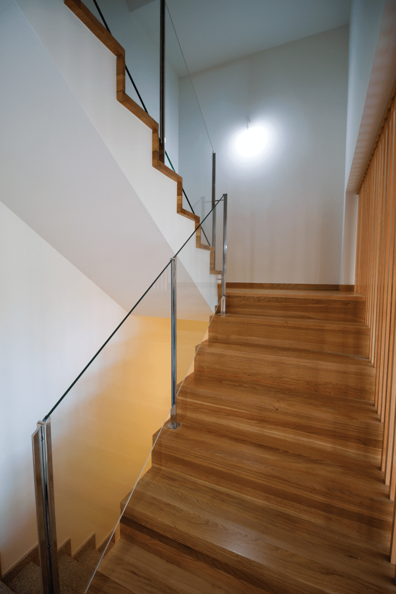 Un conjunto de escaleras de madera con barandilla de vidrio.