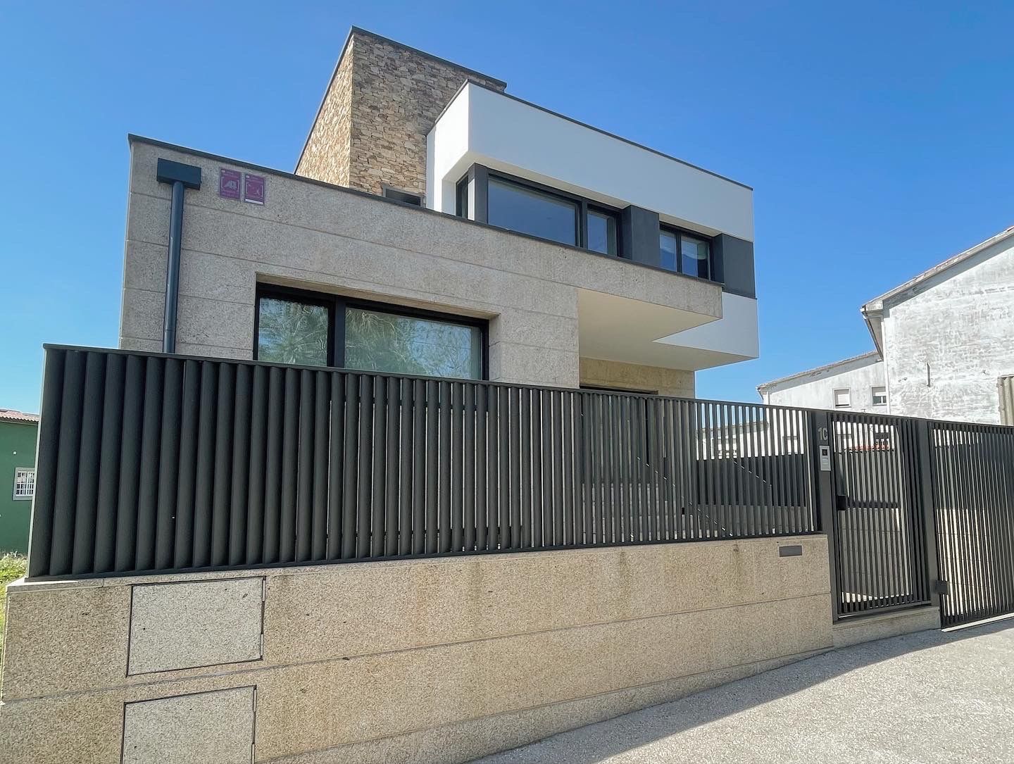 Una casa moderna con una valla delante de ella.