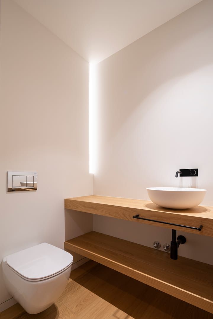 Un baño con inodoro, lavabo y encimera de madera.