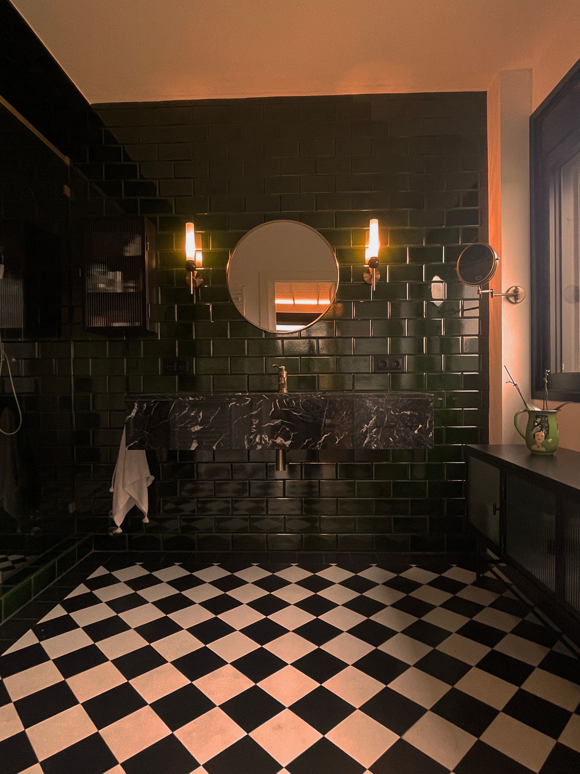 Un baño con azulejos negros y suelo de cuadros.