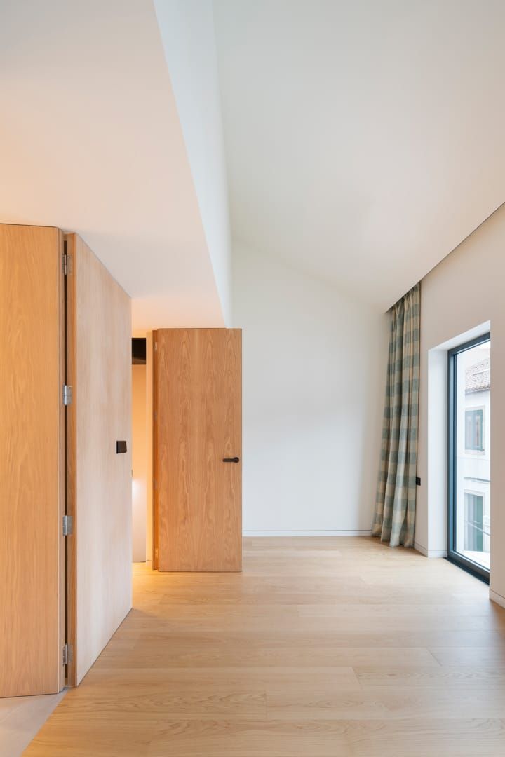 Una habitación vacía con suelo de madera y paredes blancas.
