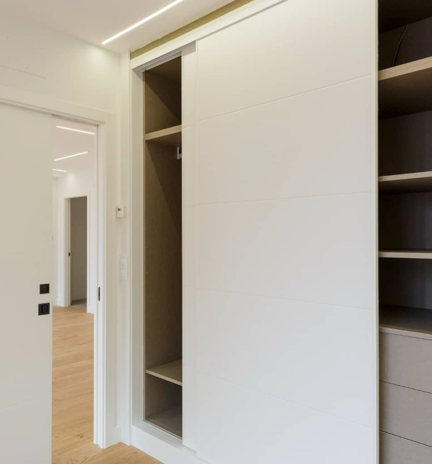 Un vestidor con puertas corredizas y estantes.