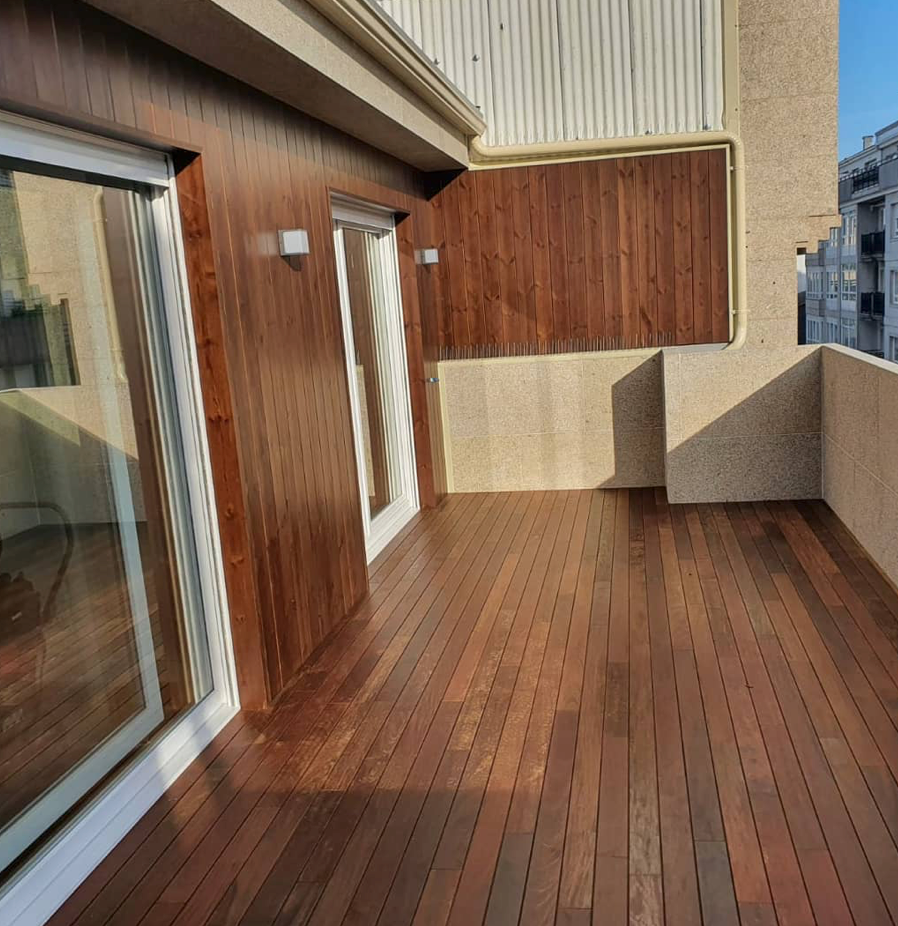 Un balcón con terraza de madera y puertas corredizas de vidrio.