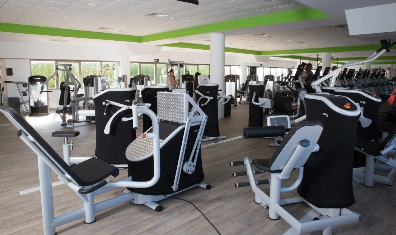 Un gimnasio con muchas máquinas y un techo verde.